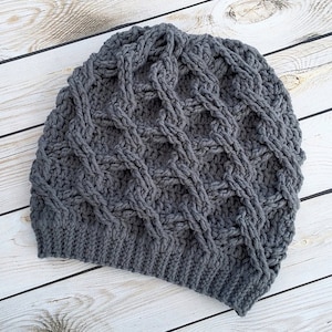 Puede incluir: Un gorro de punto gris con un patrón de trenza.