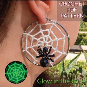 May include: A silver hoop earring with a white crocheted spiderweb design and a black beaded spider. The image includes the text "CROCHET PDF PATTERN" and "Glow in the dark!"