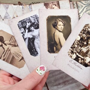 May include: A collection of vintage-style photographs featuring women in elegant attire. The sepia-toned images are held in a decorative album, showcasing a nostalgic aesthetic. One photo includes the text "E. Halden, Philadelphia."