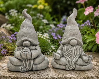 Peut inclure: Deux nains de jardin en pierre grise en position assise. Le nain de gauche a les mains jointes en geste de prière, tandis que celui de droite a les mains posées sur les genoux en posture de méditation. Ils portent des chapeaux pointus.