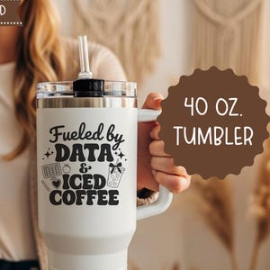May include: A white 40 oz. tumbler with a handle and a straw. The tumbler has the text "Fueled by DATA & ICED COFFEE" in black. The tumbler is designed for cold beverages and includes a straw. The words "STRAW INCLUDED" are at the top.