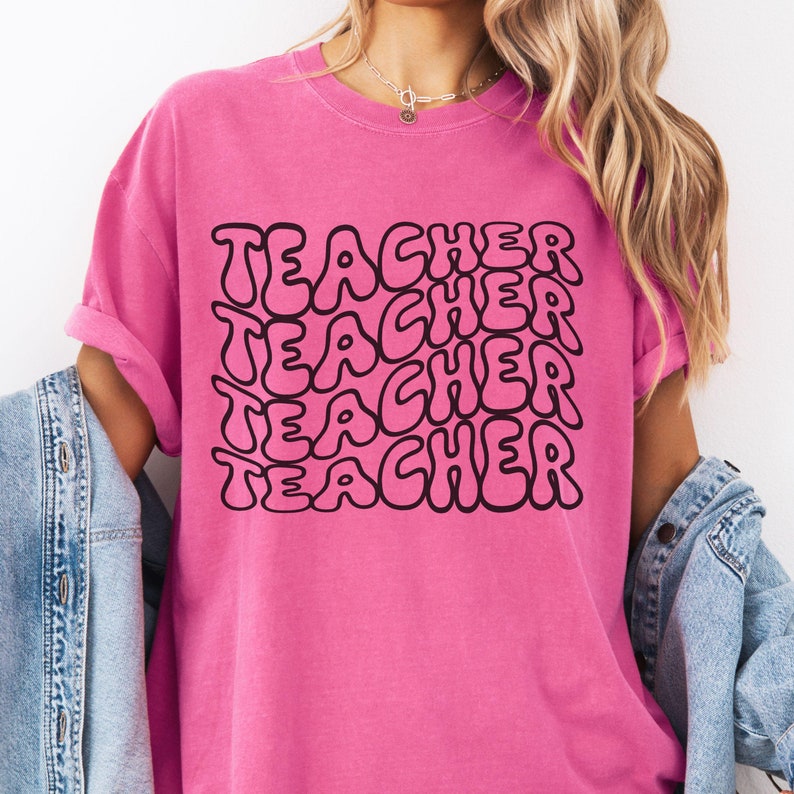 May include: Pink t-shirt with the word "TEACHER" repeated in a retro, bubble-style font.