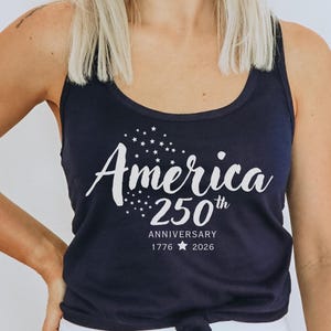Pu&ograve; includere: Canotta blu navy con la scritta bianca "America 250th Anniversary 1776 2026" e dettagli a stella. La canotta &egrave; a girocollo.