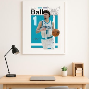 以下が含まれることがあります： バスケットボール選手、ラメロ・ボールがシャーロット・ホーネッツのユニフォームを着てバスケットボールを持っているフレーム入りポスター。ポスターは、チームのロゴと選手の名前が入った、ターコイズと白の配色です。数字の1が大きく表示されています。