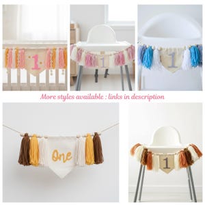 May include: A collection of handmade fabric banners with tassels and wooden beads. The banners feature the number "1" or the word "One" in various colors, perfect for a first birthday celebration. The banners are in shades of pink, white, yellow, brown, and blue.