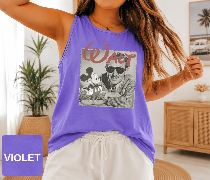 Peut inclure: Un d&eacute;bardeur violet sans manches avec une impression graphique en noir et blanc de Walt Disney et Mickey Mouse. Le mot Walt est imprim&eacute; dans une grande police rouge stylis&eacute;e au-dessus de l'image. Le d&eacute;bardeur a une encolure ronde.