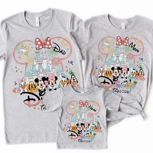 May include: Three gray t-shirts with Disney-themed designs. Each shirt features a castle, Disney characters, and the text "Disney Trip 2024". One shirt says "Dad", another "Mom", and the third "Noah".