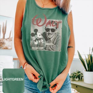 Peut inclure: Un d&eacute;bardeur vert clair sans manches avec une impression graphique de Walt Disney portant des lunettes de soleil &agrave; c&ocirc;t&eacute; de Mickey Mouse. Le mot Walt est imprim&eacute; dans une grande police stylis&eacute;e au-dessus de l'image en noir et blanc.