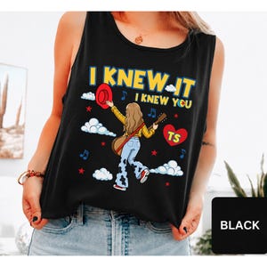 May include: A black sleeveless tank top featuring a graphic illustration of a person with long hair wearing a yellow plaid shirt and cow-print pants, holding a guitar and a red hat. The text reads I KNEW IT I KNEW YOU with a red heart labeled TS.