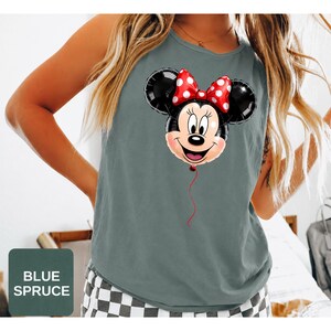 Op de afbeelding: Een mouwloos hemd in de kleur blauwspar met een grafische print van een Minnie Mouse-ballon. De ballon is zwart met een rode strik met witte stippen, en een dun rood touwtje hangt naar beneden vanaf de onderkant van het gezicht.