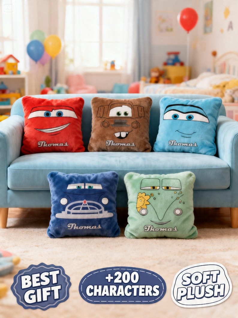 May include: Five plush throw pillows featuring cartoon car designs in red, brown, blue, dark blue, and green. Each pillow has a smiling car face and the name "Thomas" embroidered on it. The pillows are arranged on a light blue couch.
