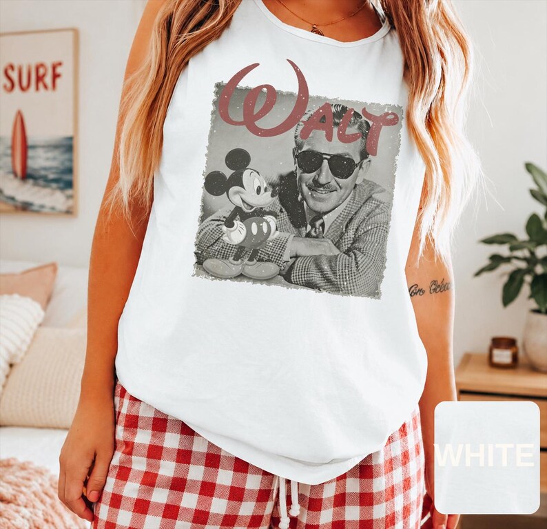 Peut inclure: Un d&eacute;bardeur blanc sans manches avec une impression graphique en noir et blanc de Walt Disney portant des lunettes de soleil &agrave; c&ocirc;t&eacute; de Mickey Mouse. Le mot WALT est imprim&eacute; dans une grande police vieillie brun-rouge au-dessus de l'image.