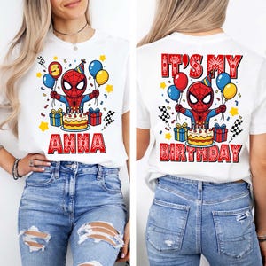 Puede incluir: Camiseta blanca con un dise&ntilde;o colorido de Spider-Man sosteniendo globos y una tarta de cumplea&ntilde;os. La parte delantera dice "ANNA" en rojo, la trasera dice "IT'S MY BIRTHDAY". El dise&ntilde;o incluye estrellas, confeti y cajas de regalo.