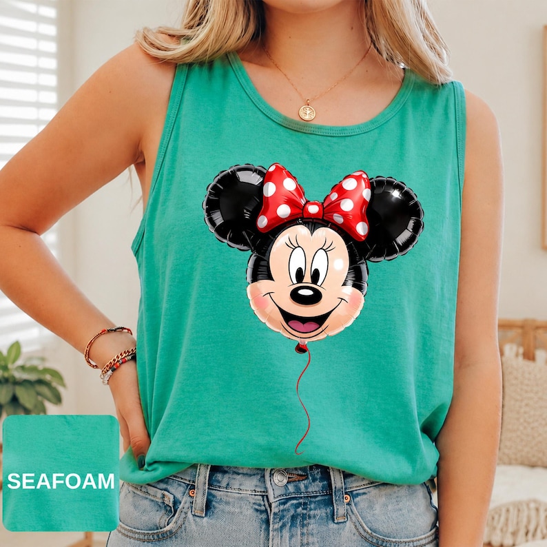 Op de afbeelding: Een zeegroene mouwloze tanktop met een grafische print van een Minnie Mouse-ballon. De ballon is zwart met een rode strik met witte stippen, en een dun rood touwtje hangt naar beneden vanaf de onderkant van het gezicht van het figuur.