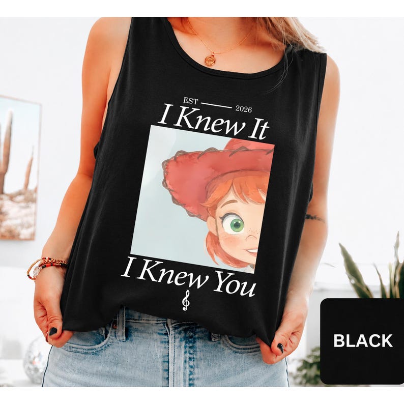 May include: A black sleeveless tank top featuring a graphic print of a cartoon character with red hair and a red hat. The text reads EST 2026 I Knew It I Knew You with a treble clef symbol below. The design is centered on the front of the garment.
