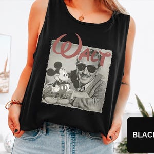 Peut inclure: Un d&eacute;bardeur noir sans manches avec une impression graphique de Walt Disney et Mickey Mouse dans un style vintage en noir et blanc. Le mot Walt est imprim&eacute; dans une grande police cursive rose poudr&eacute; au-dessus de l'image. Col rond.