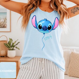 May include: A light blue sleeveless tank top featuring a graphic of the character Stitch designed as a blue balloon with pink inner ears and large black eyes. Below the balloon, the word Stitch is written in a cursive blue script font.