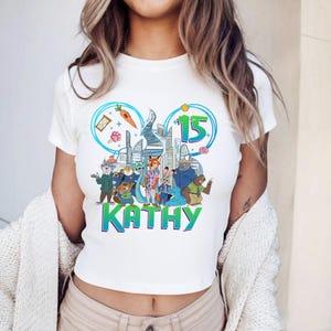 May include: A white ceramic mug with a black handle and the text "But First, Coffee" in a bold, black font. The mug is set against a blurred background, suggesting a cozy setting.