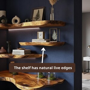 May include: Wooden floating shelves with natural live edges are mounted on a dark blue wall. The shelves display decorative items, including framed art, a clock, books, and vases. The text on the image says: "The shelf has natural live edges."