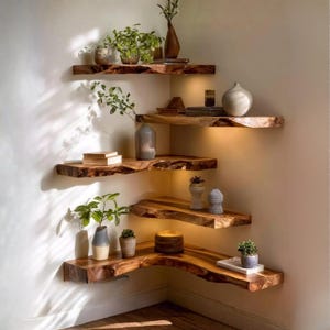 May include: Five wooden corner shelves with live edges, arranged in a staggered formation. Each shelf displays decorative items such as plants in vases, small pots, and a candle. The shelves are illuminated, creating a warm ambiance.