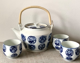 May include: A white teapot with a blue and white floral design and a bamboo handle, along with four matching teacups.