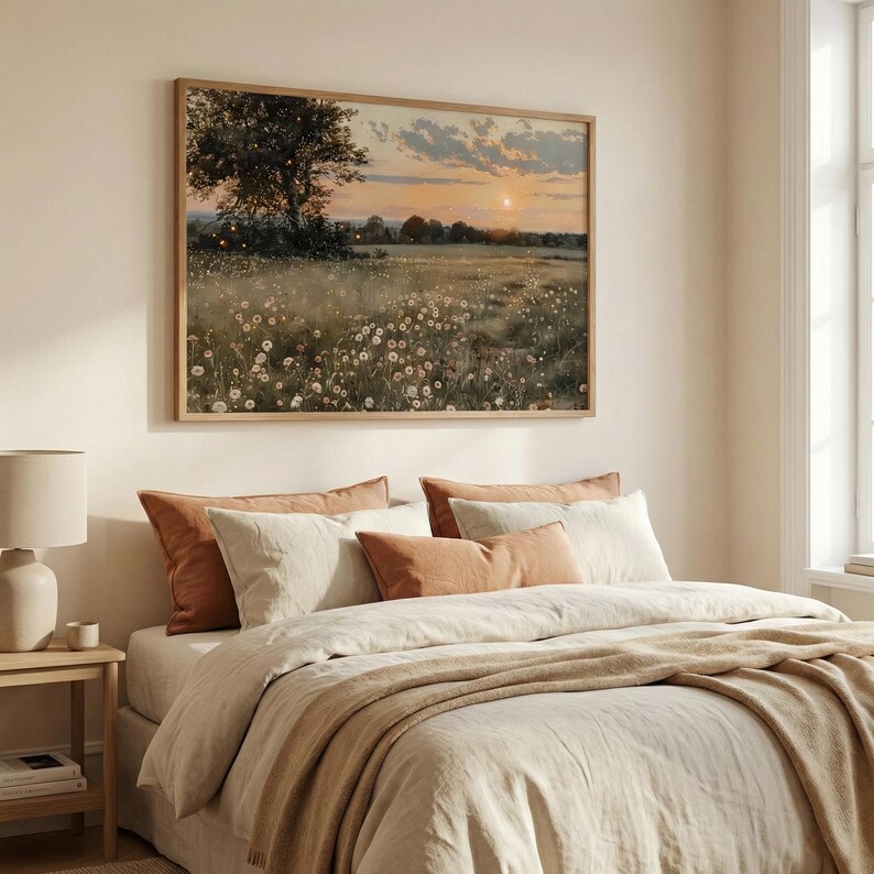 K&ouml;nnte beinhalten: Ein gerahmtes Landschaftsgem&auml;lde zeigt ein Feld mit Wildblumen unter einem Sonnenuntergangshimmel. Das Kunstwerk wird &uuml;ber einem Bett mit neutralfarbener Bettw&auml;sche und dekorativen Kissen in Beige- und Rostt&ouml;nen ausgestellt.