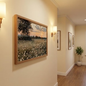 K&ouml;nnte beinhalten: Gerahmtes Landschaftsgem&auml;lde, das ein Feld mit Wildblumen unter einem Sonnenuntergangshimmel zeigt. Das Kunstwerk befindet sich in einem hellbraunen Holzrahmen und h&auml;ngt an einer cremefarbenen Wand. Der Flur zeigt weitere gerahmte Kunstwerke und Wandleuchten.
