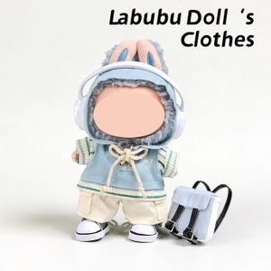 Puede incluir: Una muñeca con una sudadera con capucha azul con orejas de conejo, auriculares y una mochila a juego. La muñeca también lleva una camisa a rayas, pantalones cortos color crema y zapatillas blancas. El texto "Labubu Doll 's Clothes" está en la parte superior.