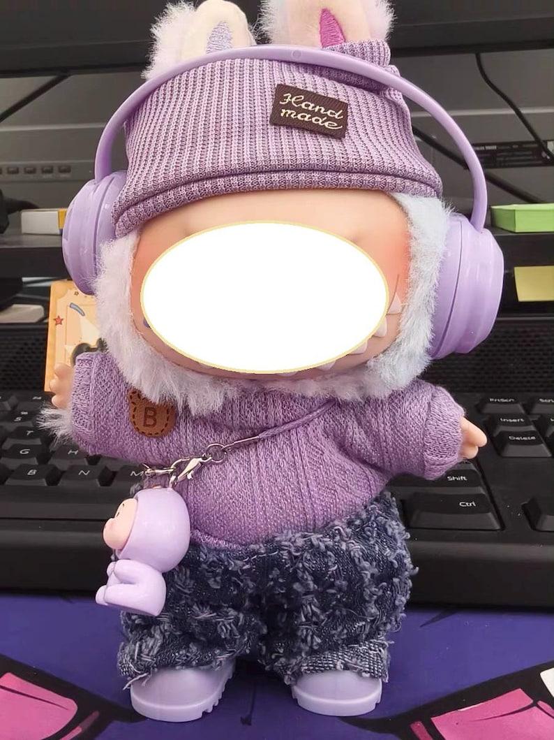 Puede incluir: Mu&ntilde;eca de peluche con gorro de punto morado con orejas de conejo, auriculares a juego y un su&eacute;ter. La mu&ntilde;eca tiene pantalones vaqueros y una peque&ntilde;a figura morada adjunta. El gorro tiene una etiqueta "Hand made".