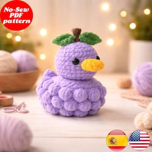 Pode incluir: Um pato de crochê roxo feito à mão com bico amarelo, olhos pretos e folhas verdes na cabeça. O pato é feito de fio macio e tem um corpo texturizado. A imagem inclui o texto "No-Sew PDF pattern" em um círculo vermelho.