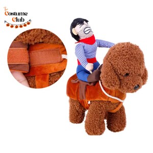 May include: A brown dog costume with a cowboy rider. The cowboy is wearing a blue plaid shirt, red scarf, and blue pants. The dog costume has a saddle and adjustable straps. The Costume Club logo is in the top left corner.