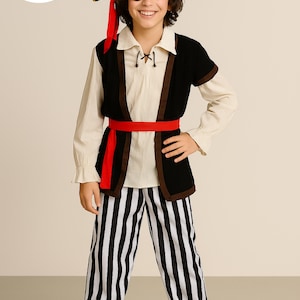 Pode incluir: Uma fantasia de pirata infantil. Inclui um chapéu de três pontas preto com caveira, tapa-olho e faixa vermelha. O traje inclui camisa branca, colete preto e calças listradas em preto e branco. O logotipo The Costume Club é visível.