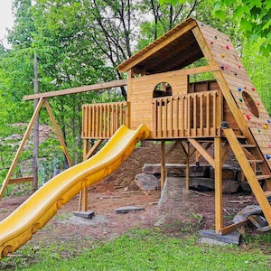 Puede incluir: Parque infantil de madera con tobogán amarillo, rocódromo con presas de colores y una pequeña casita. El parque está rodeado de hierba verde y árboles.