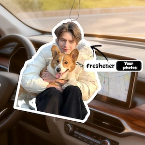 Peut inclure: Désodorisant de voiture personnalisé avec une personne tenant un chien corgi. Le désodorisant porte le mot "freshener" et le texte "Your photos". L'arrière-plan montre un intérieur de voiture.
