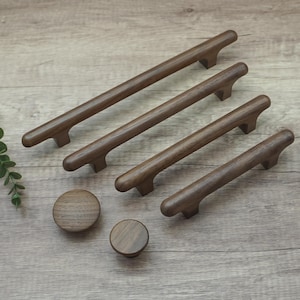 Pode incluir: Um conjunto de ferragens de madeira para armários, incluindo quatro puxadores e dois puxadores redondos. Os puxadores variam em comprimento, com um acabamento castanho escuro. Os puxadores e puxadores são feitos de madeira maciça.