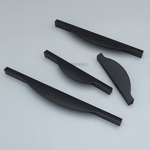 May include: Four matte black cabinet pulls with a twisted, curved design. The pulls have a rectangular shape at each end and a smooth, ergonomic curve in the center. The hardware is designed for easy installation and a modern aesthetic.