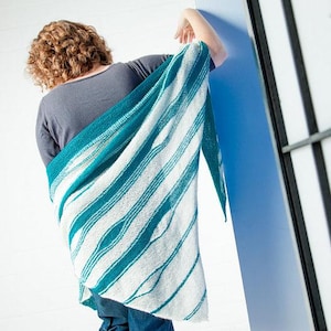 Könnte beinhalten: Ein Schal mit türkisfarbenen und weißen Streifen. Der Schal ist über die Schultern einer Person gelegt. Die Streifen verlaufen diagonal von links oben nach rechts unten. Der Schal ist aus weichem Strickmaterial.