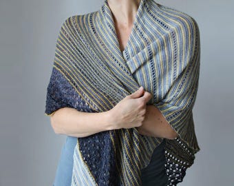 Könnte beinhalten: Ein gestrickter Schal in Blau-, Grau- und Gelbtönen. Der Schal hat ein Streifenmuster mit einem dunkelblauen Rand und einem zarten Spitzensaum. Das Kleidungsstück ist über den Schultern drapiert.