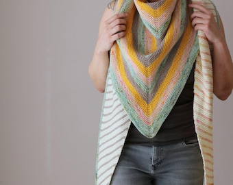 Könnte beinhalten: Ein handgestrickter Schal in Dreiecksform mit gelben, rosa, grünen und grauen Streifen. Die Kanten weisen ein cremefarbenes und beigefarbenes Streifenmuster auf. Der Schal ist zum Tragen um Hals und Schultern konzipiert.