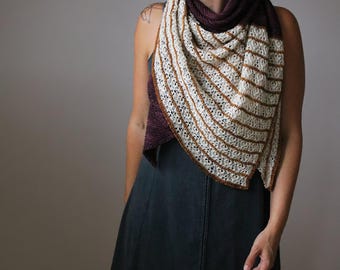 Könnte beinhalten: Ein gestrickter Schal in Dreiecksform. Der Schal hat einen cremefarbenen Körper mit braunen Streifen und einen tiefvioletten Kragen. Die Kanten haben ein zartes Lochmuster. Der Schal ist über die Schultern drapiert.