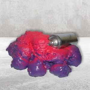 May include: A purple and red slime-like substance with a silver spray paint can partially submerged in it.