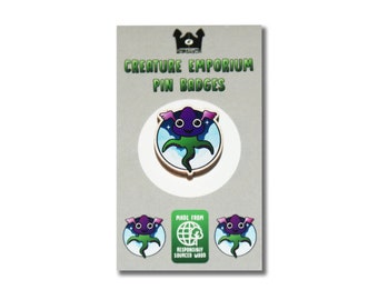 May include: A purple and green creature with wings and big eyes on a round wooden pin badge. The badge says "Creature Emporium Pin Badges" and "Made from Responsibly Sourced Wood".