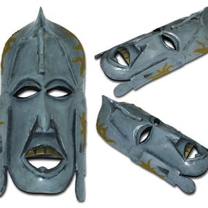 May include: Three gray wooden masks with gold accents. The masks have a tribal design and are carved in a human-like shape.