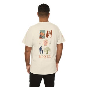 Op de afbeelding: Crèmekleurig t-shirt met een grafisch ontwerp met illustraties van een gezin, zon en boom. Het woord "BIQEL" is in een vetgedrukte lettertype onder de illustraties gedrukt. Het shirt is gemaakt van een zachte, getextureerde stof.