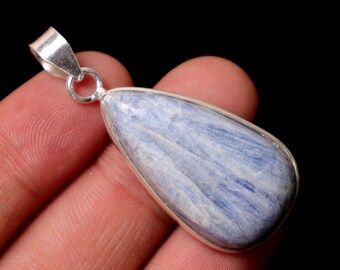 May include: A teardrop-shaped pendant with a blue and white stone set in a silver-colored metal frame. The pendant has a loop at the top for a chain. The stone has a natural, textured appearance.