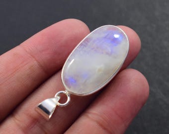 May include: Oval-shaped moonstone pendant with a silver bail. The moonstone has a pearly white base with iridescent blue and purple flashes. The pendant is set in a silver bezel.