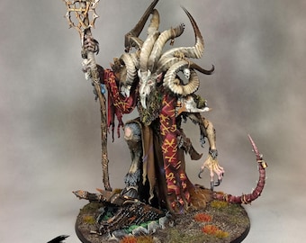May include: A detailed miniature figure of a horned creature with a staff, wearing a red and brown robe. The figure is on a circular base with a dark raven silhouette in the corner. The Ravenwolf Modeling Studio logo is visible.