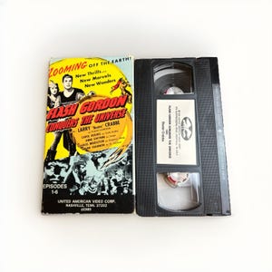 May include: A vintage VHS tape of "Flash Gordon Conquers the Universe" with a yellow and black cover. The cover features a movie poster with actors and the title. The tape is black and open, with the title label visible.
