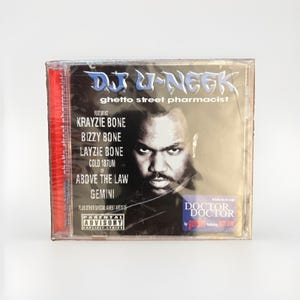 May include: A music CD titled Ghetto Street Pharmacist by DJ U-Neek in a clear plastic jewel case. The cover features a black and white portrait of a man, the artist name, a list of guest artists, a Parental Advisory label, and a Doctor Doctor sticker.