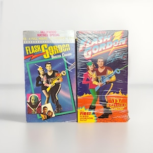 May include: Two vintage VHS tapes of "Flash Gordon" movies. The tapes feature colorful artwork with images of the characters and the movie title. One tape says "Buster Crabbe" and the other says "13 Episode Serial".